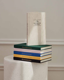 Original linen journal standing on a stack of journals in other colors.