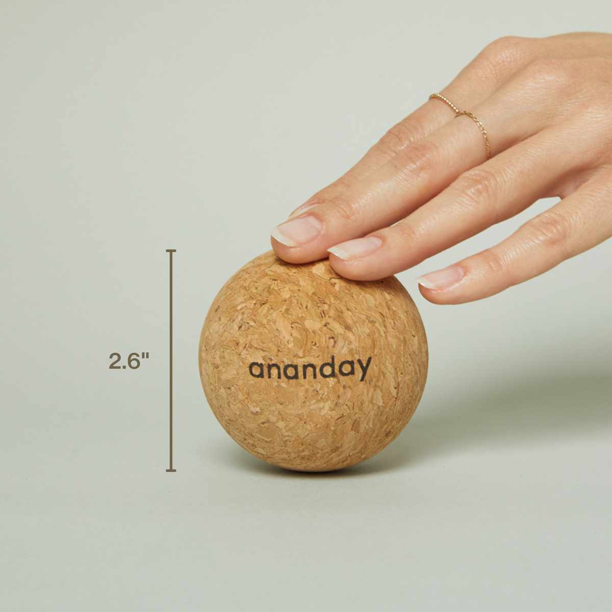 Hand resting on an Ananday cork ball beside a visible 2.6-inch measurement.