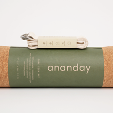 Folded Ananday yoga strap resting on a rolled cork yoga mat.