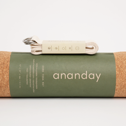 Folded Ananday yoga strap resting on a rolled cork yoga mat.