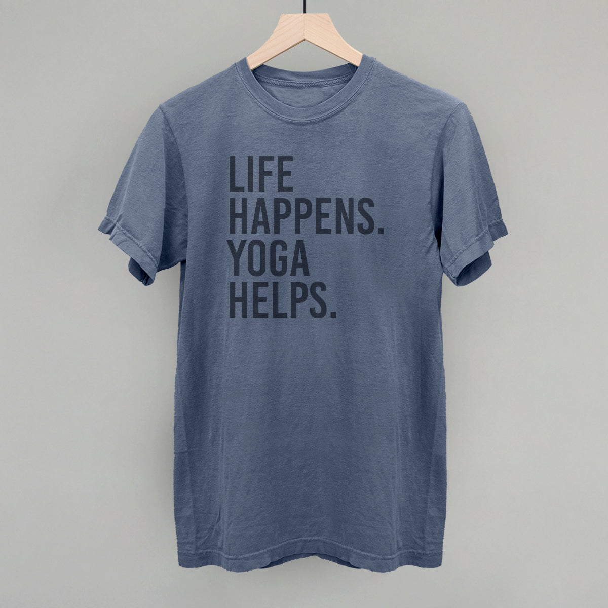 Blue short-sleeve shirt on a hanger with visible printed text, Life Happens. Yoga Helps.