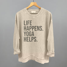 Cream textured long-sleeve top on a hanger with visible printed text, Life Happens. Yoga Helps.