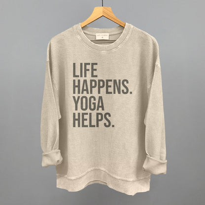 Cream textured long-sleeve top on a hanger with visible printed text, Life Happens. Yoga Helps.