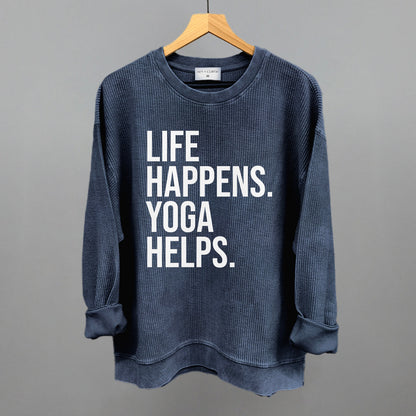 Dark blue textured long-sleeve top on a hanger with visible printed text, Life Happens. Yoga Helps.