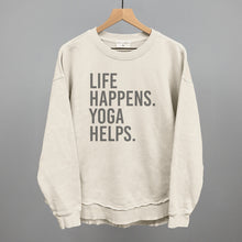 Cream long-sleeve top on a hanger with visible printed text, Life Happens. Yoga Helps.