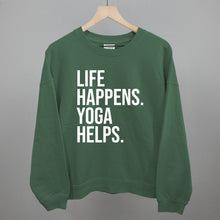 Green sweatshirt on a hanger with visible printed text, Life Happens. Yoga Helps.
