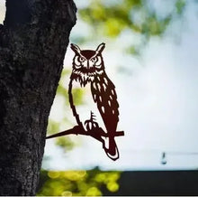 Black owl silhouette decoration attached to a tree trunk.