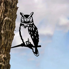 Black owl silhouette decoration attached to a tree trunk.