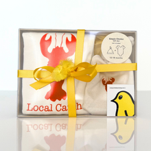 Local Catch natural cotton baby romper, hat, and blanket set arranged in a clear gift box