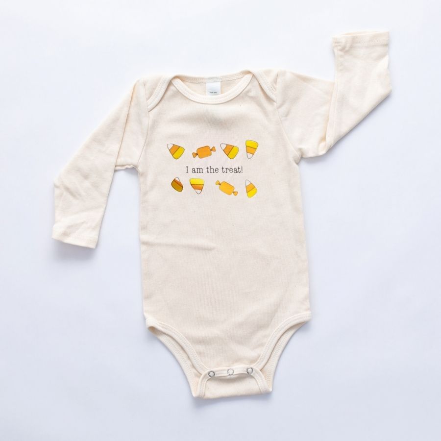 Natural cotton long-sleeve baby romper with an I Am the Treat candy design laid flat