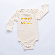 Natural cotton long-sleeve baby romper with an I Am the Treat candy design laid flat