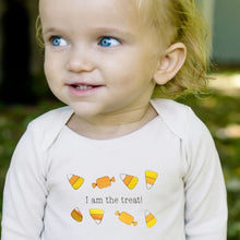 Toddler wearing a natural cotton long-sleeve romper with an I Am the Treat candy design