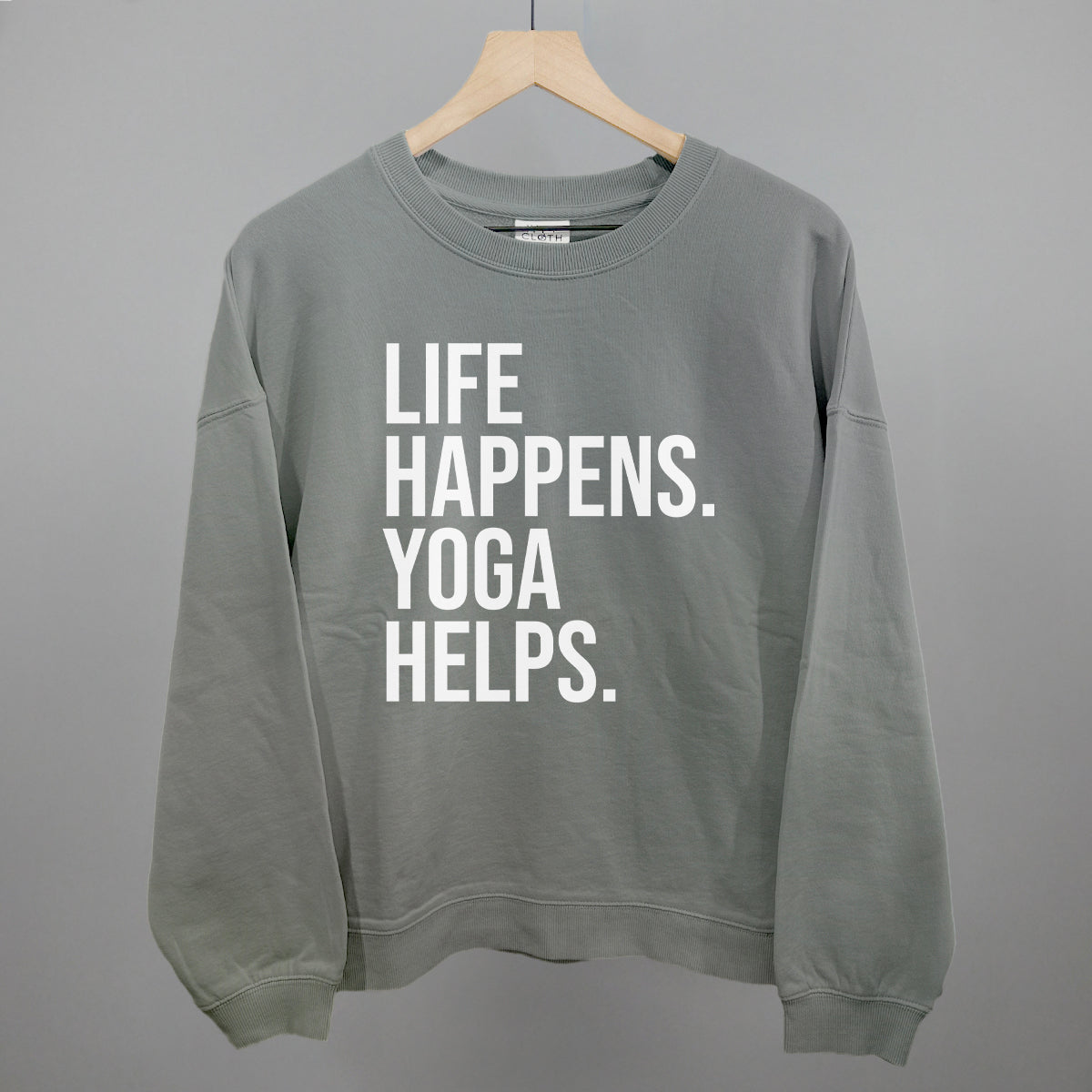 Gray sweatshirt on a hanger with visible printed text, Life Happens. Yoga Helps.