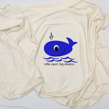 Close view of a natural cotton Big Dreams baby blanket with a blue whale and waves
