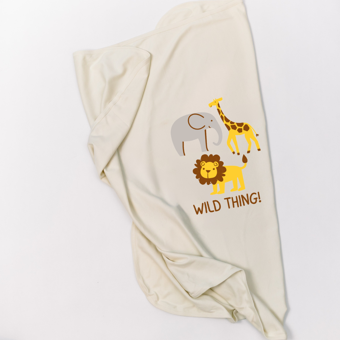 Natural cotton Wild Thing baby blanket with elephant, giraffe, and lion graphics folded on white