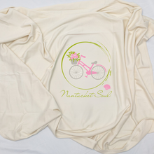 Close view of a natural cotton Nantucket Soul baby blanket with a pink bicycle and flowers