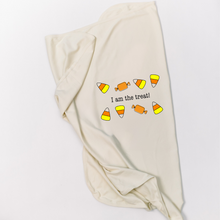 Natural cotton baby blanket with an I Am the Treat candy design folded on a white background