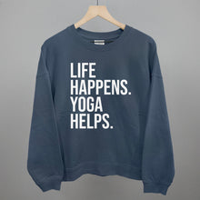 Blue sweatshirt on a hanger with visible printed text, Life Happens. Yoga Helps.