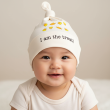 Baby wearing a natural cotton knotted hat with an I Am the Treat candy design