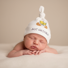 Sleeping newborn wearing a natural cotton knotted hat with a yellow Just Hatched chick design