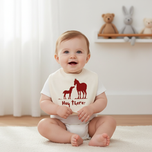 Baby wearing a white bib with red horse and foal silhouettes and “Hay there!” text.