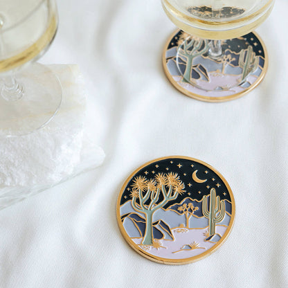 Two Moonlight Joshua Tree coasters styled beneath wine glasses on a white table