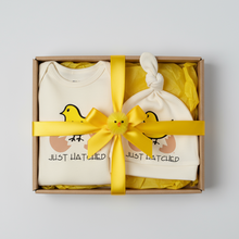 Just Hatched natural cotton baby romper and hat set arranged in a gift box with a yellow ribbon