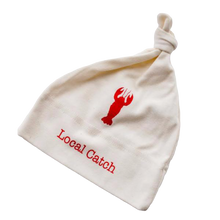 White knotted baby hat with red lobster graphic and “Local Catch” text on a transparent background.