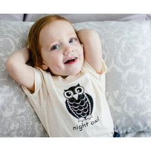 Child wearing a natural cotton short-sleeve romper with a black Night Owl design
