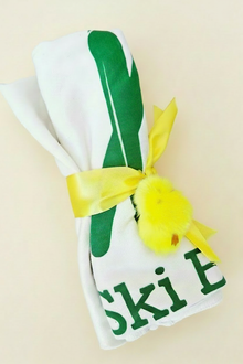 Rolled natural cotton Ski Bum baby blanket tied with a yellow ribbon
