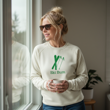 Woman wearing a natural cotton Ski Bum sweatshirt while holding a mug by a window